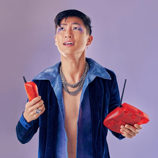 Photo téléphone de mode et homme confus en studio isolé sur fond violet gen z déclin des appels téléphoniques punk et modèle gay du japon maquillé avec un téléphone rétro vintage et une technologie obsolète