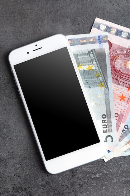 Téléphone portable et argent sur fond gris Concept de paiement et d'épargne