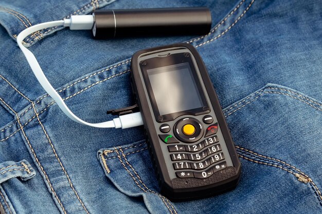 Un téléphone portable et une banque d'alimentation sur un fond de jeans dans la nature