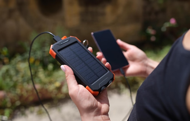 Un téléphone portable et une banque d'énergie solaire en main en gros plan