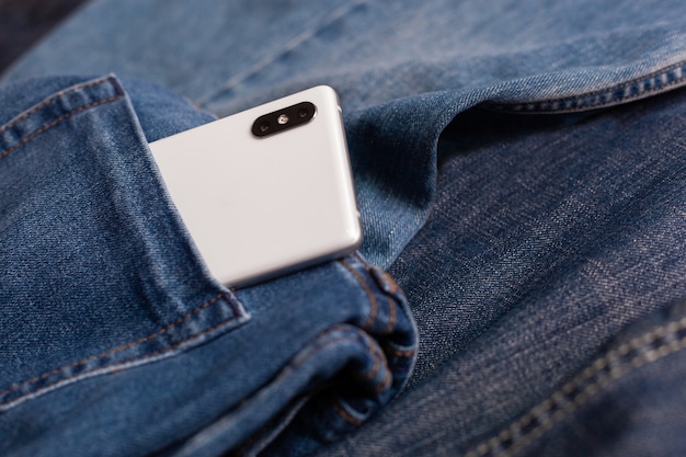 Téléphone portable blanc sur un jean bleu
