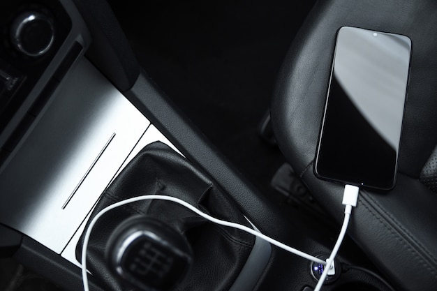 Téléphone portable, charge de la batterie du smartphone, chargement dans la prise de voiture se bouchent