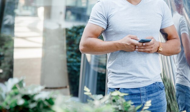 Téléphone portable entre les mains des hommes. Un homme écrit un message sur un téléphone portable. Torse d'un homme.