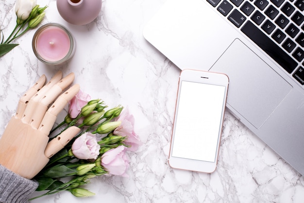 Téléphone portable et main en bois avec des fleurs roses sur marbre