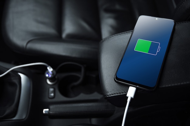 Téléphone portable, smartphone, téléphone portable est chargé, chargez la batterie avec un chargeur USB à l'intérieur de la voiture. intérieur de voiture noire moderne.