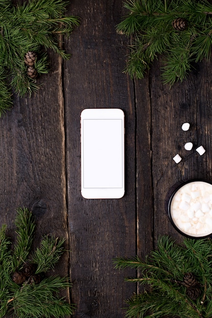 Téléphone portable sur une table en bois avec un sapin de Noël et du cacao