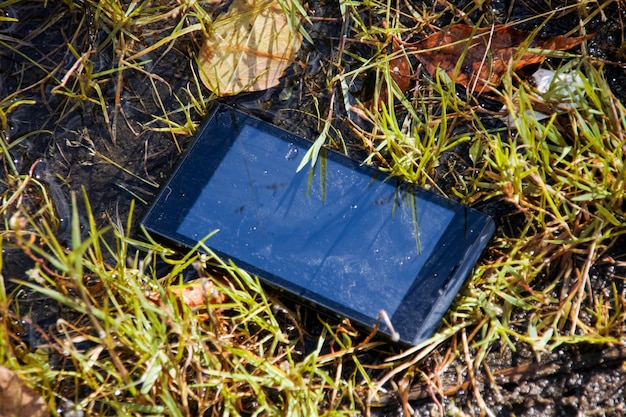 Le téléphone portable tactile se trouve dans une flaque d'eau