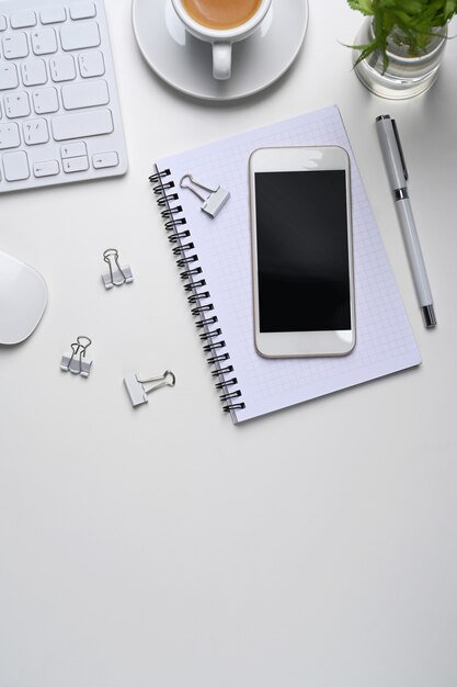 Téléphone portable, tasse à café, ordinateur portable et espace de copie sur fond blanc.