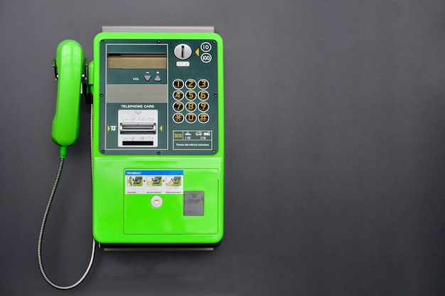 Téléphone public vert sur fond de couleur noire