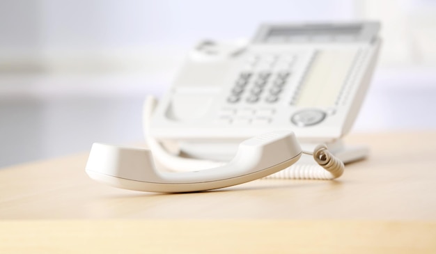 Téléphone avec récepteur décroché sur une table en bois au bureau