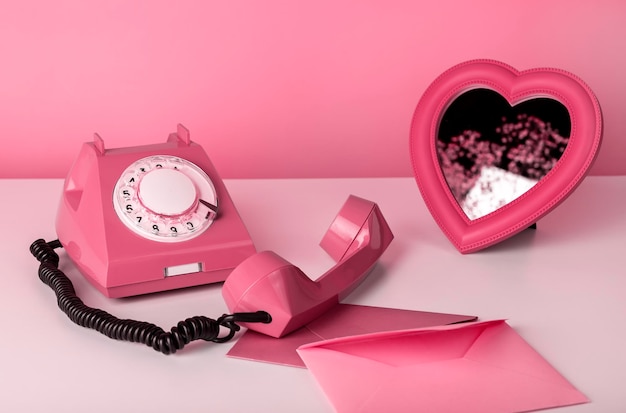 Téléphone rétro avec miroir coeur et enveloppes à table nature morte en couleur rose concept de saint valentin...