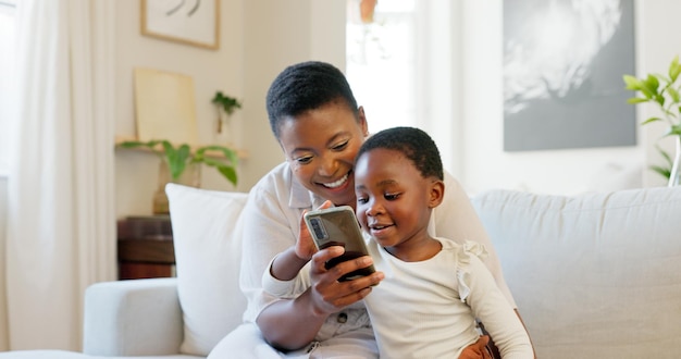 Téléphone surprise et famille noire se liant sur un canapé dans la maison ou le salon à la maison avec un jeu d'apprentissage éducatif ou d'esport amusant Souriez heureux ou choqué mère et enfant sur la technologie mobile avec un visage wow