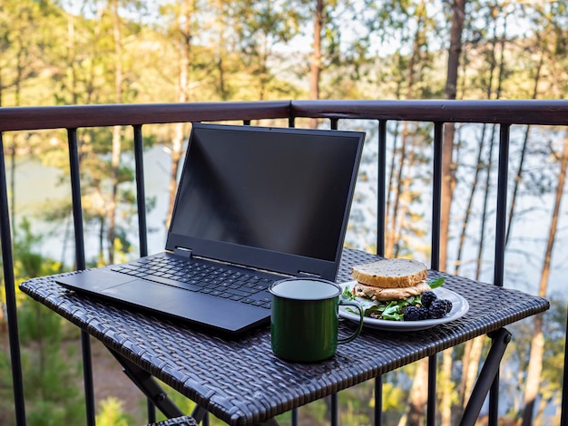 Télétravail sur une terrasse face à une forêt et un lac télétravail nomade numérique