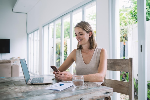 Télétravailleur féminin en pause à l'aide d'un smartphone