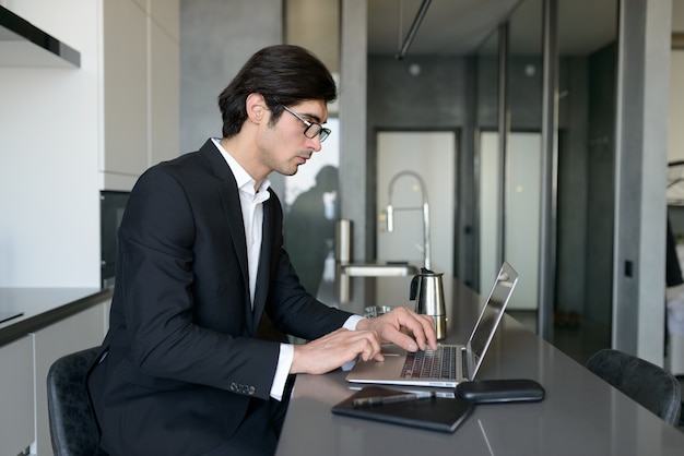 Télétravailleur homme travaille à la maison avec un ordinateur portable