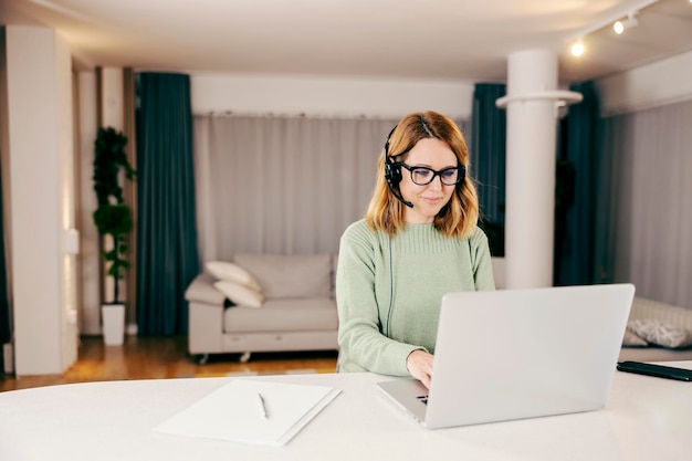 Une télétravailleuse travaillant en ligne depuis sa maison confortable sur son ordinateur portable et en tapant