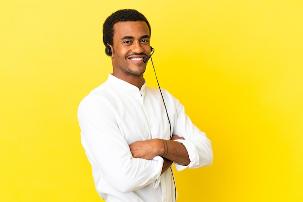 Télévendeur afro-américain travaillant avec un casque sur fond jaune isolé avec les bras croisés et impatient