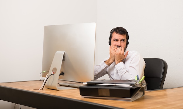 Un télévendeur dans un bureau est un peu nerveux et a peur de mettre ses mains à la bouche