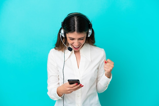 Télévendeur femme italienne travaillant avec un casque isolé sur fond bleu surpris et envoyant un message