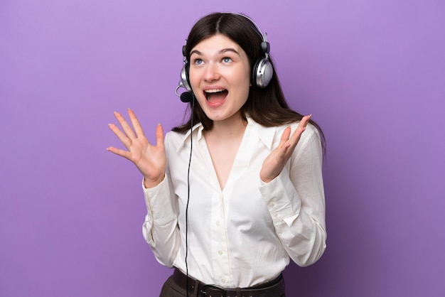 Télévendeur femme russe travaillant avec un casque isolé sur fond violet avec une expression faciale surprise