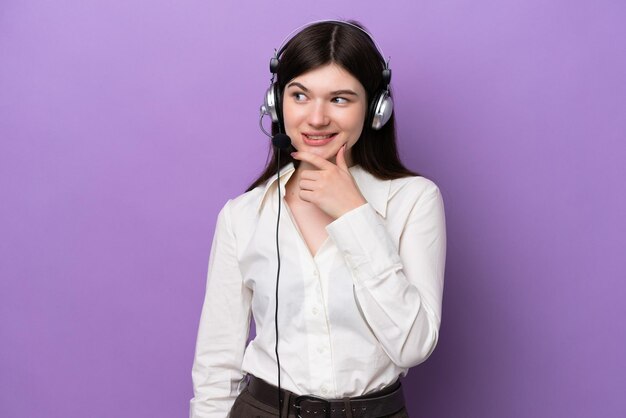 Photo télévendeur femme russe travaillant avec un casque isolé sur fond violet regardant sur le côté