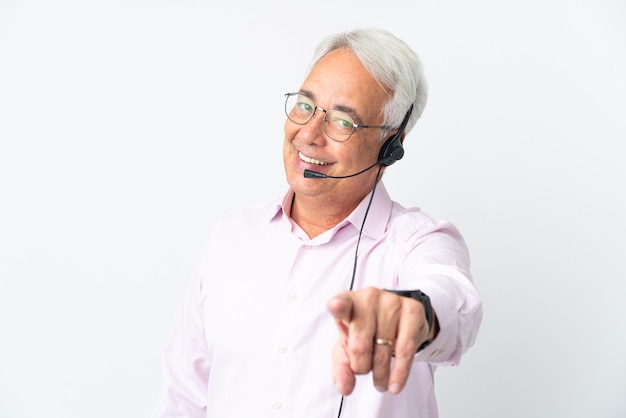 Télévendeur homme d'âge moyen travaillant avec un casque isolé sur fond blanc pointant vers l'avant avec une expression heureuse