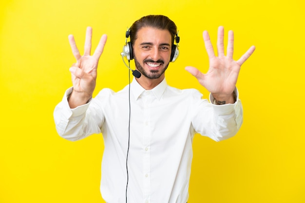 Télévendeur homme caucasien travaillant avec un casque isolé sur fond jaune comptant huit avec les doigts