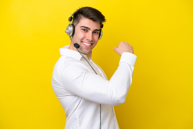 Télévendeur homme caucasien travaillant avec un casque isolé sur fond jaune faisant un geste fort