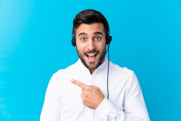 Télévendeur homme travaillant avec un casque sur un doigt pointé bleu sur le côté