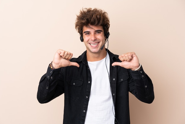 Télévendeur homme travaillant avec un casque sur un mur isolé fier et satisfait de lui-même