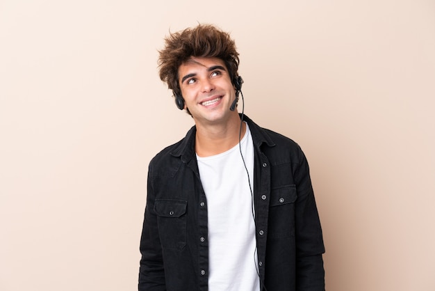 Télévendeur homme travaillant avec un casque sur un mur isolé en riant et en levant