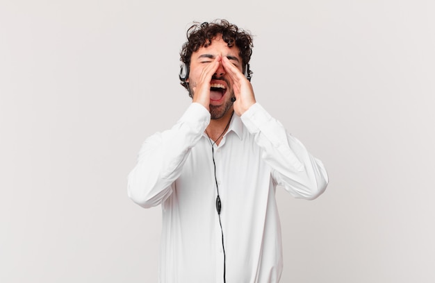 Télévendeur se sentant heureux, excité et positif, criant avec les mains près de la bouche, appelant