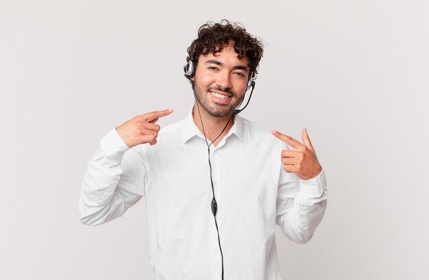 Télévendeur souriant avec confiance pointant vers son propre large sourire, attitude positive, détendue et satisfaite