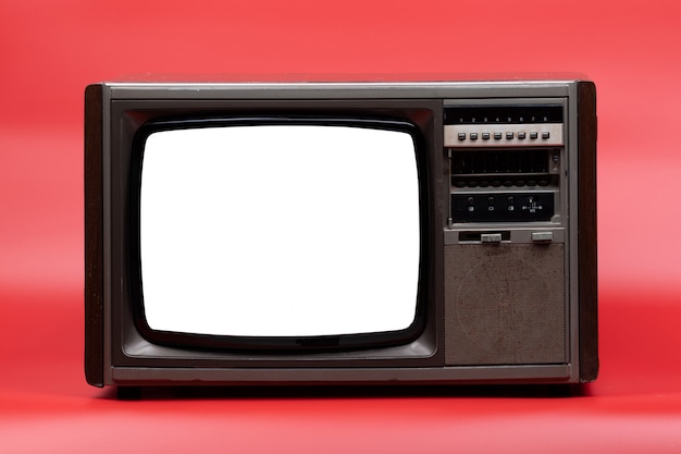Télévision vintage avec écran découpé sur fond rouge.