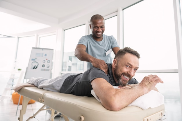 Tellement confortable. Homme gentil ravi positif allongé sur le canapé médical tout en étant de bonne humeur