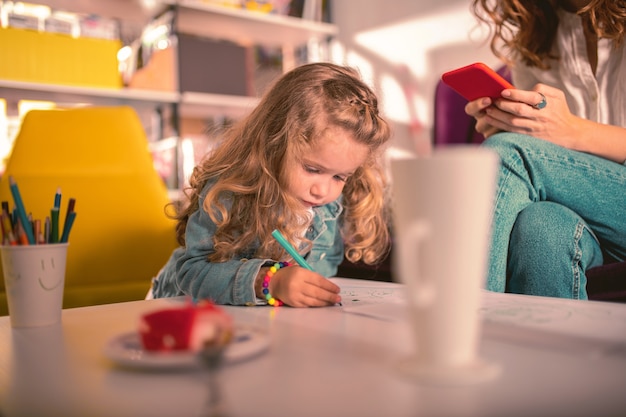 Tellement ennuyé. Charmante enfant blonde s'inclinant la tête en regardant sa photo