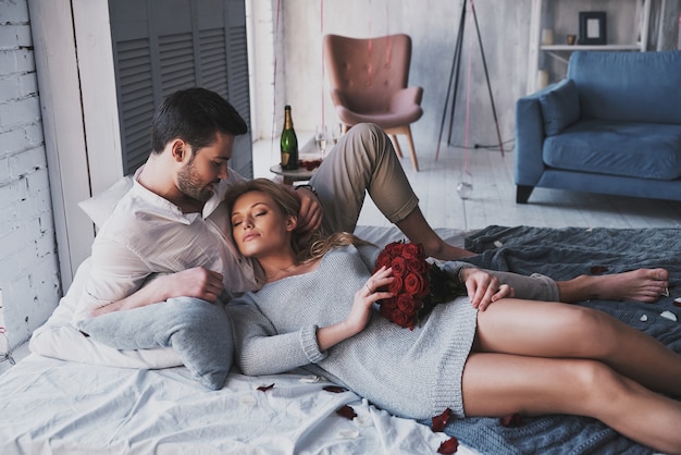 Tellement génial d'être amoureux! Beau jeune couple embrassant en position couchée sur le lit à la maison