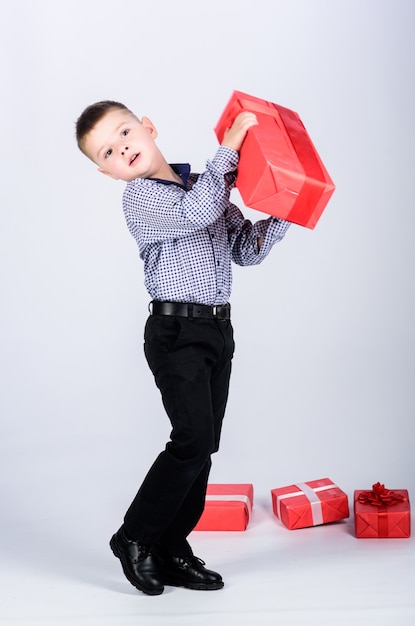 Tellement lourd. enfant heureux avec boîte présente. Noël. vendeur. Enfance heureuse. Achats. Le lendemain de Noël. Nouvelle année. petit garçon avec un cadeau pour la Saint-Valentin. Fête d'anniversaire. boîte à cadeaux lourde.