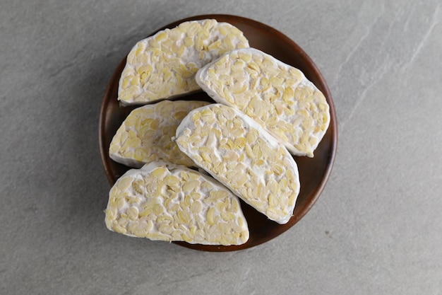 Tempeh cru ou Tempe fabriqué à partir de tranches de tempeh de soja fermenté coupées au couteau