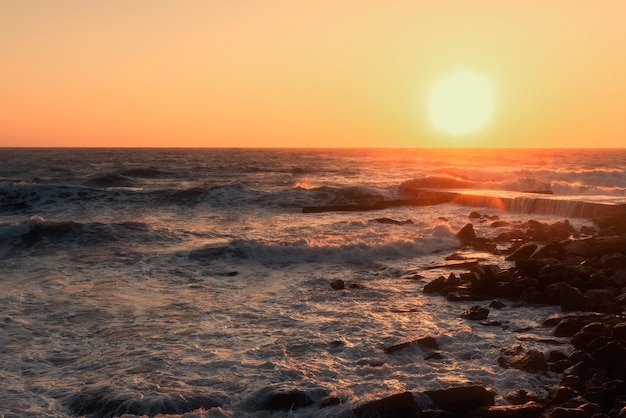 Tempête sur une côte rocheuse au coucher du soleil