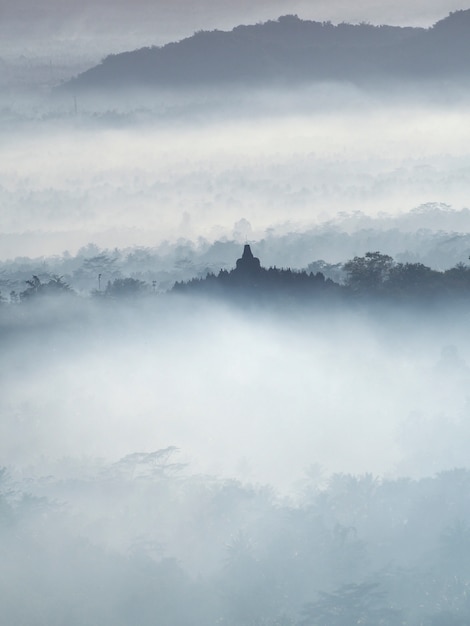 Photo temple sacré de borobudur dans un magnifique lever de soleil brumeux vu depuis la colline de setumbu