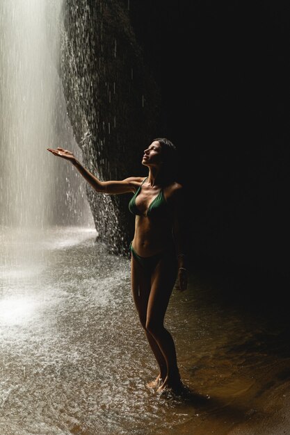 Temps chaud. Belle personne de sexe féminin démontrant sa silhouette parfaite tout en regardant la cascade, la nature sauvage