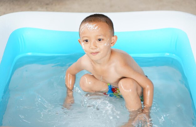 Temps chaud Garçon jouant avec de l'eau joyeusement dans la baignoire