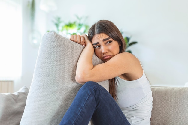 Temps difficiles. Portrait d'une femme caucasienne triste et triste tenant ses mains croisées et étreignant un gros oreiller tout en pensant à ses problèmes. Stock photo