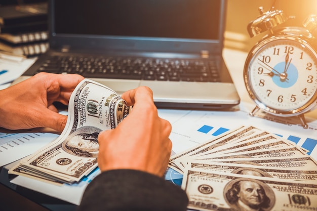 Le temps, c&#39;est de l&#39;argent. main d&#39;affaires tenant horloge de sablier et de l&#39;argent dollar.