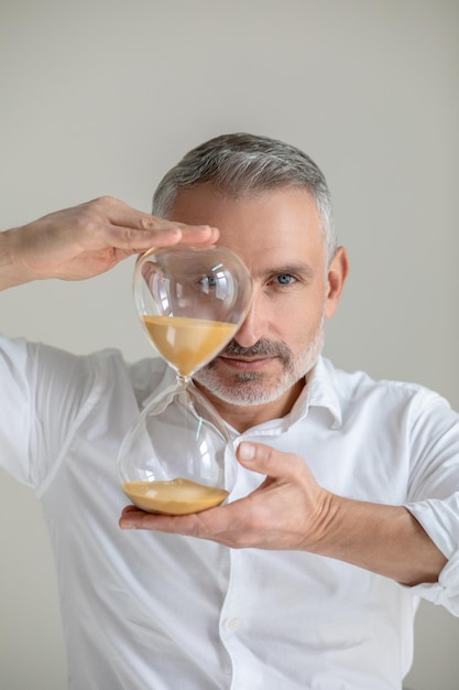 Temps. Un homme en chemise blanche avec une montre de sable dans les mains