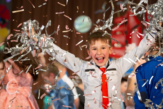 Temps magique Portrait d'un enfant très heureux avec les mains souriant tout en tombant des confettis