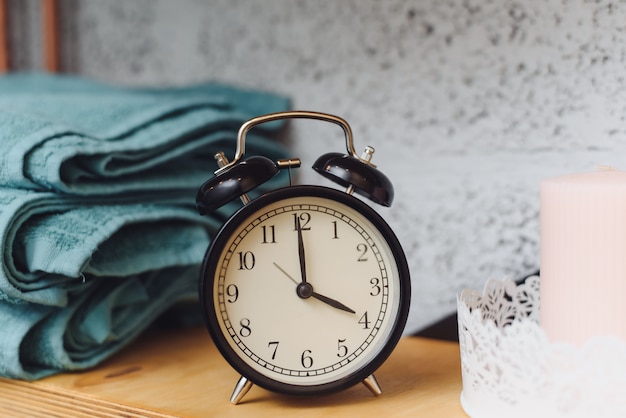 Temps de massage Horloge noire analogique sur une étagère avec des serviettes bleues et des bougies de cire. Le concept d'articles de massage