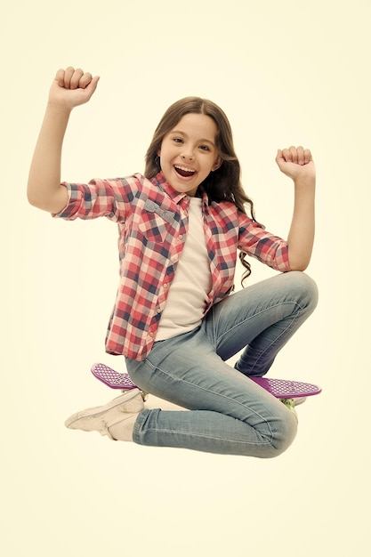 Temps de monter Kid girl excité s'assoit penny board Passe-temps adolescent moderne Fille visage heureux s'asseoir sur penny board fond blanc Conçu à l'origine comme planche à roulettes pour filles Apprendre à monter sur penny board