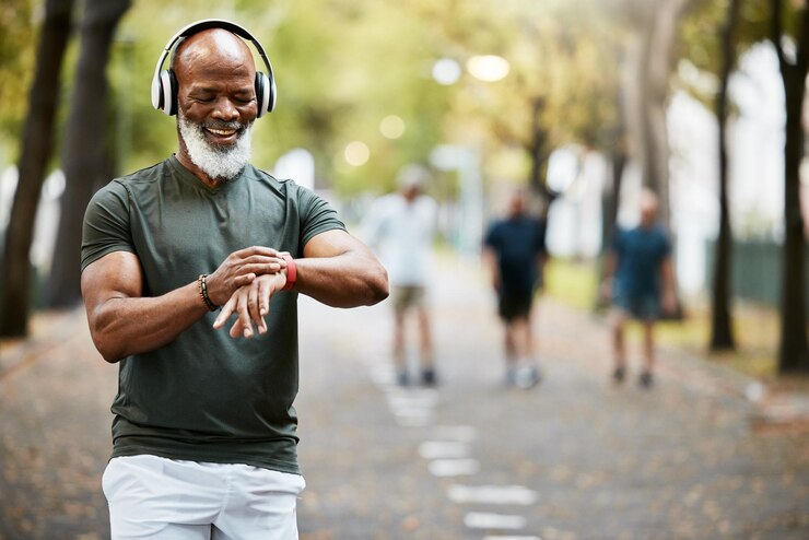 Photo temps de musique et course avec un homme noir mûr regardant sa montre pendant une course de remise en forme dans le parc entraînement bien-être et entraînement avec un athlète ou un coureur masculin senior surveillant sa santé